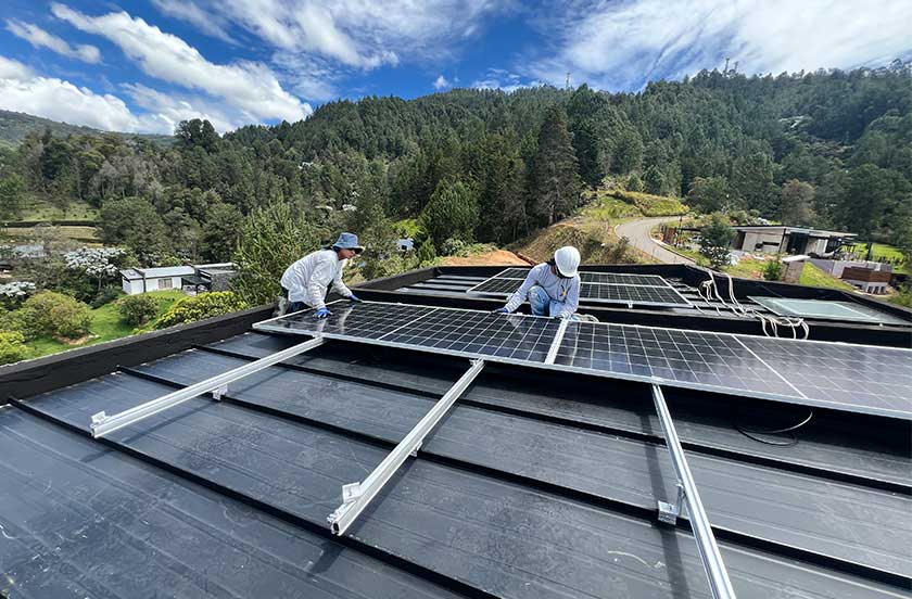 Técnicos instalando paneles solares sobre una estructura de aluminio en un techo.