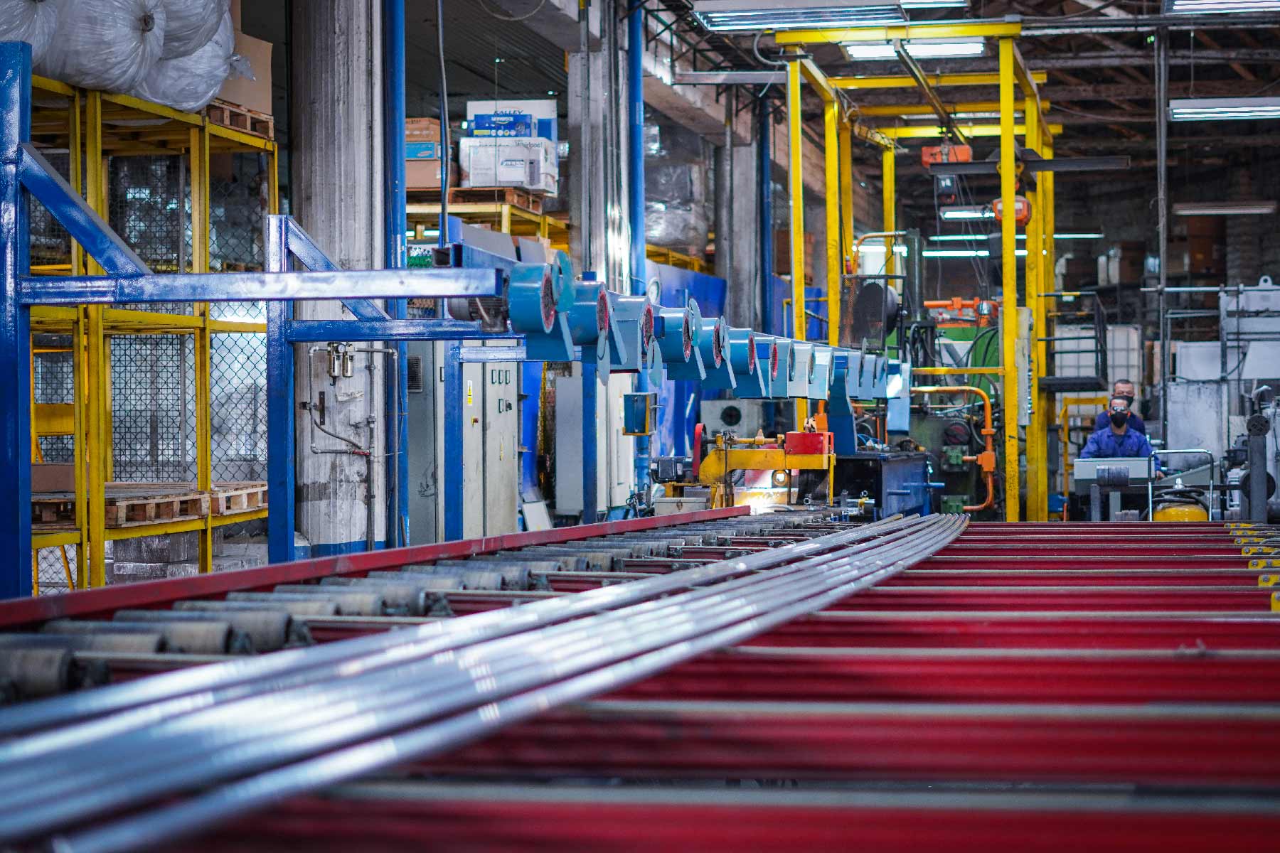 Perfiles de aluminio recién extruidos sobre la mesa de salida de la prensa, en la planta de Girardota
