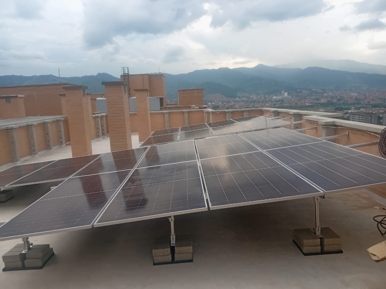 Paneles solares sobre soportes lastrados con bloques de concreto en una terraza de la ciudad.