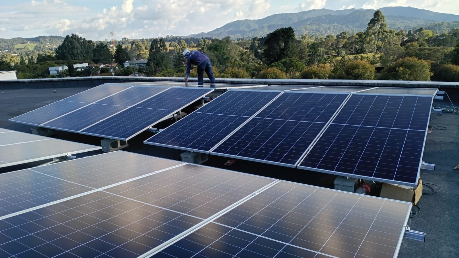 Instalador sobre una losa con varias filas de paneles solares ya montados.