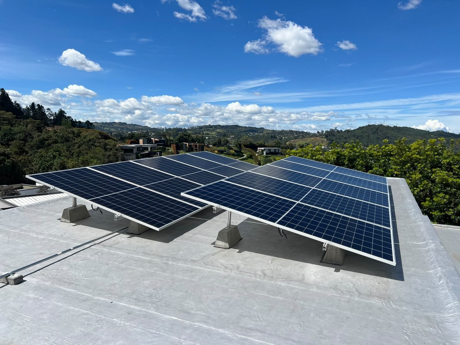 Paneles solares sobre estructura de aluminio Arcoli en una losa, con las montañas de Medellín al fondo.