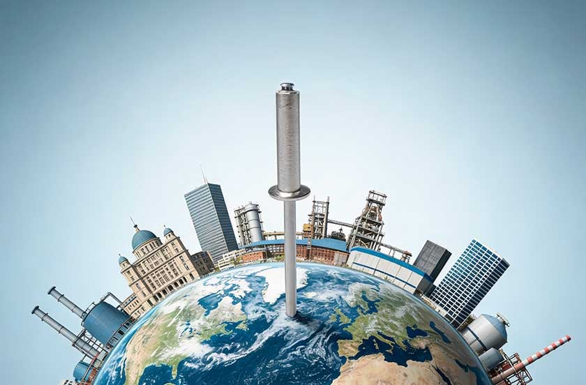 Remache gigante clavado en un globo terráqueo rodeado de edificios e industrias.