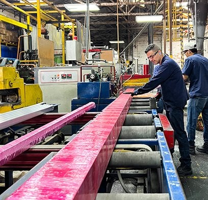 Operarios en la línea de salida de la prensa de extrusión